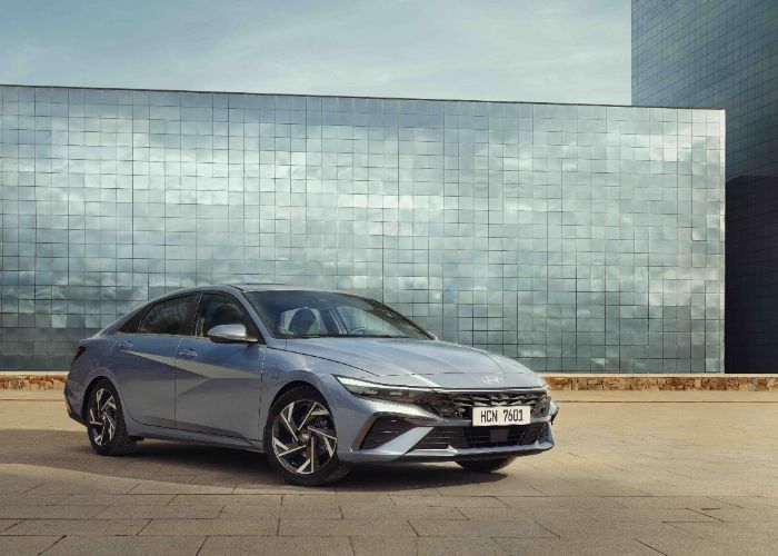 A blue hyundai elantra is parked in front of a building.
