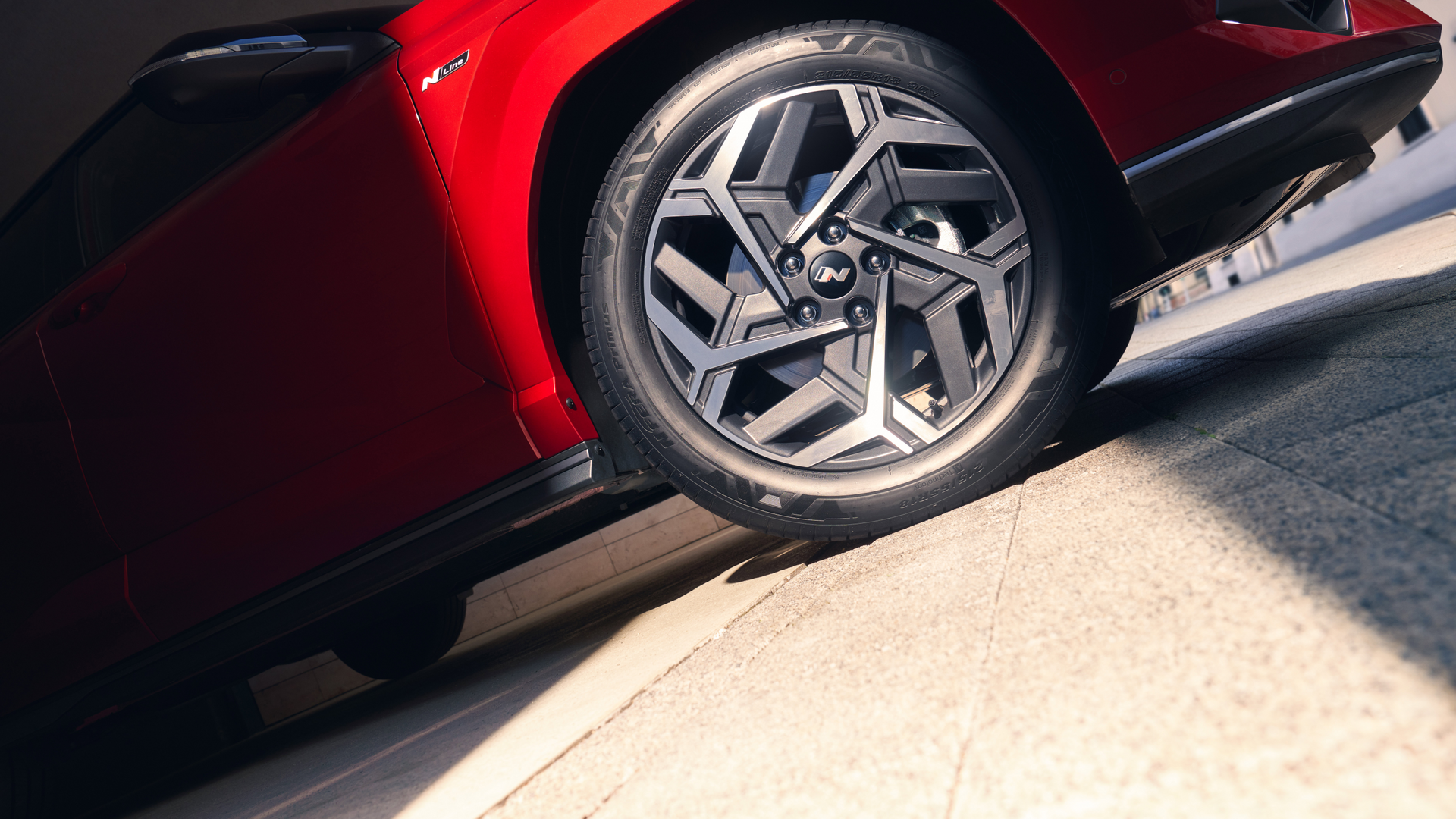 A red car is driving down a hill.