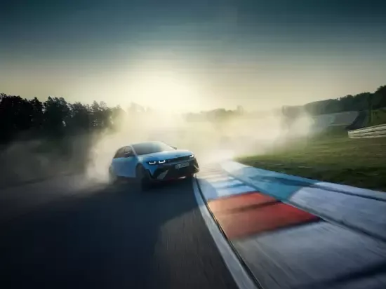 A white car is driving down a race track at sunset. Ioniq 5 N