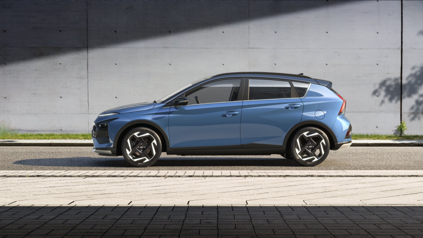 A blue car is parked on the side of the road in front of a building. Bayon
