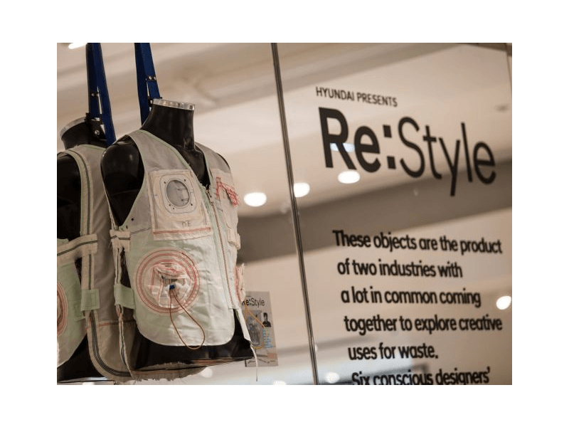 Two mannequins are hanging in front of a sign that says re style