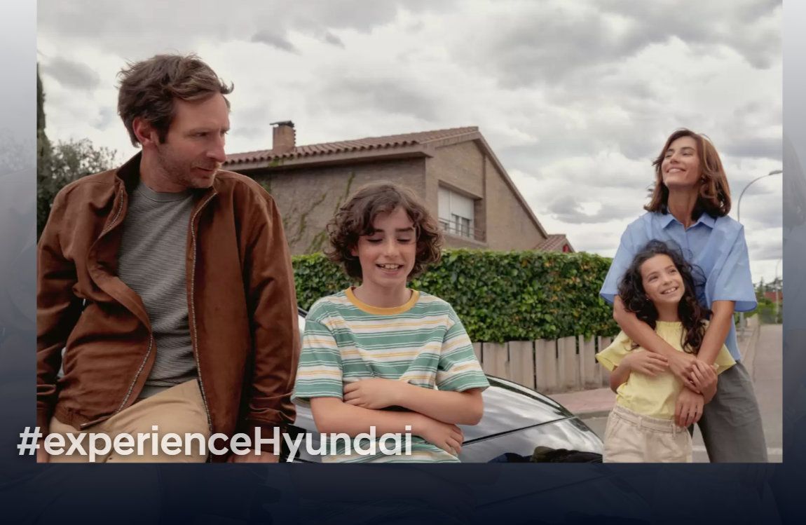 A family is sitting on the hood of a car.