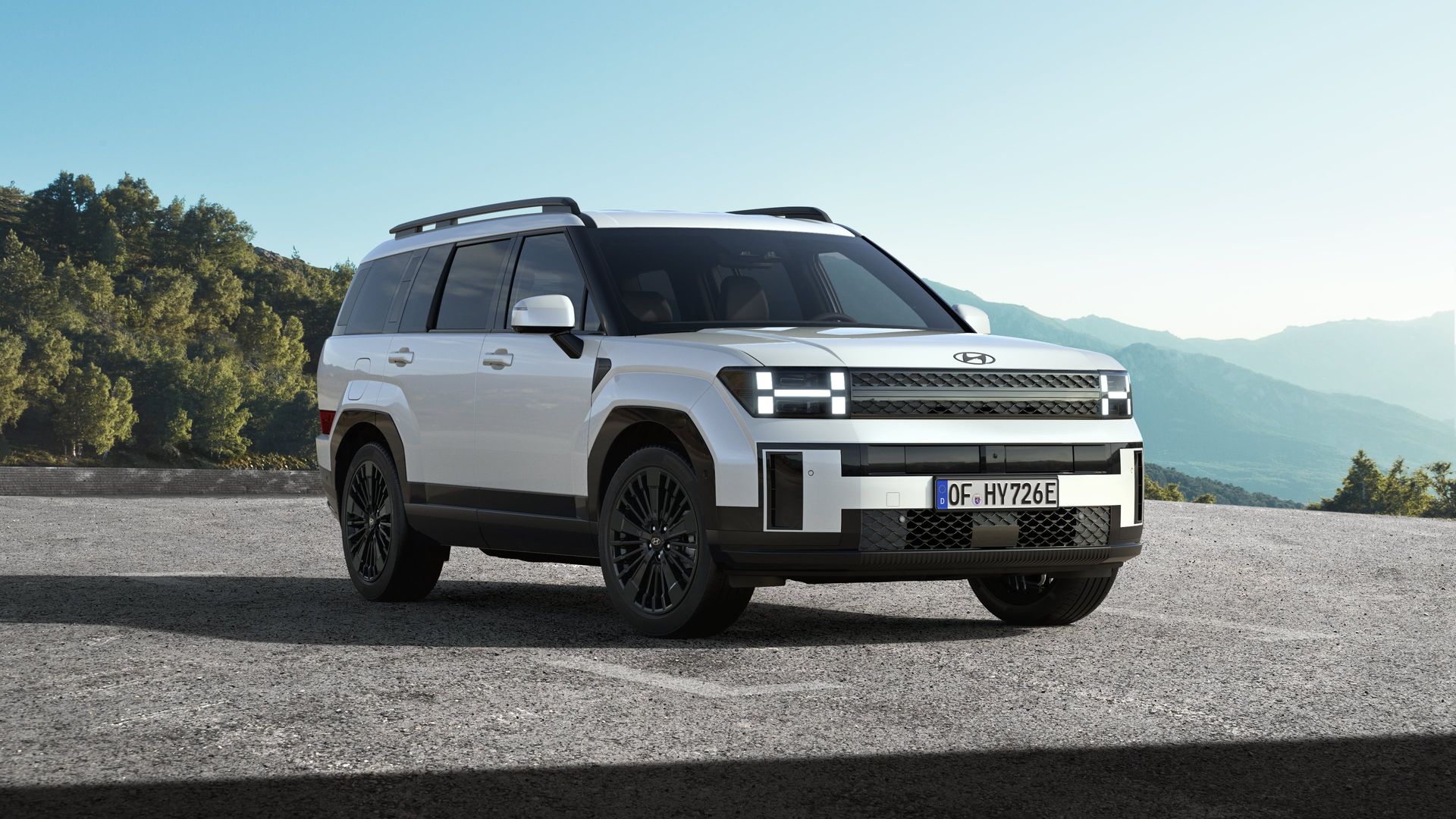 A white suv is parked on the side of a road with mountains in the background. Santa Fe
