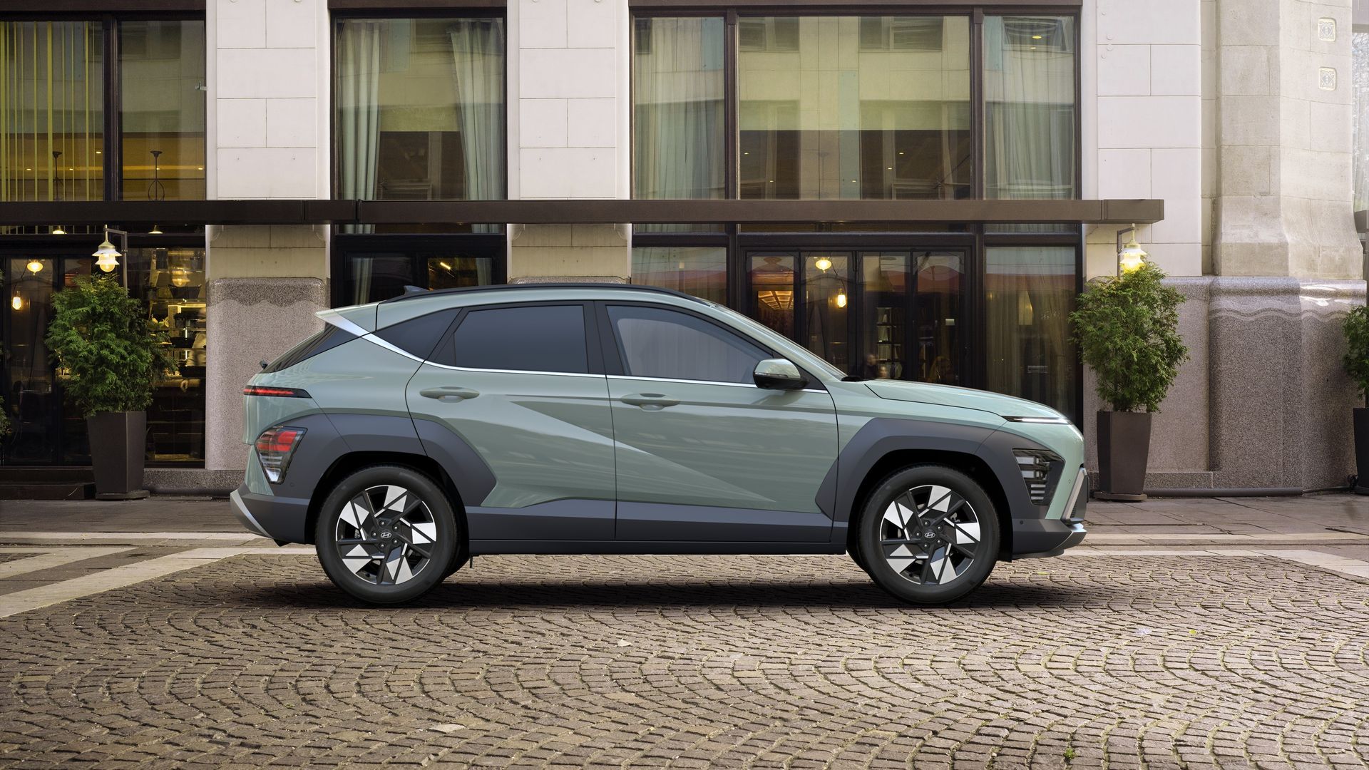 A hyundai kona is parked in front of a building on a cobblestone street. Kona