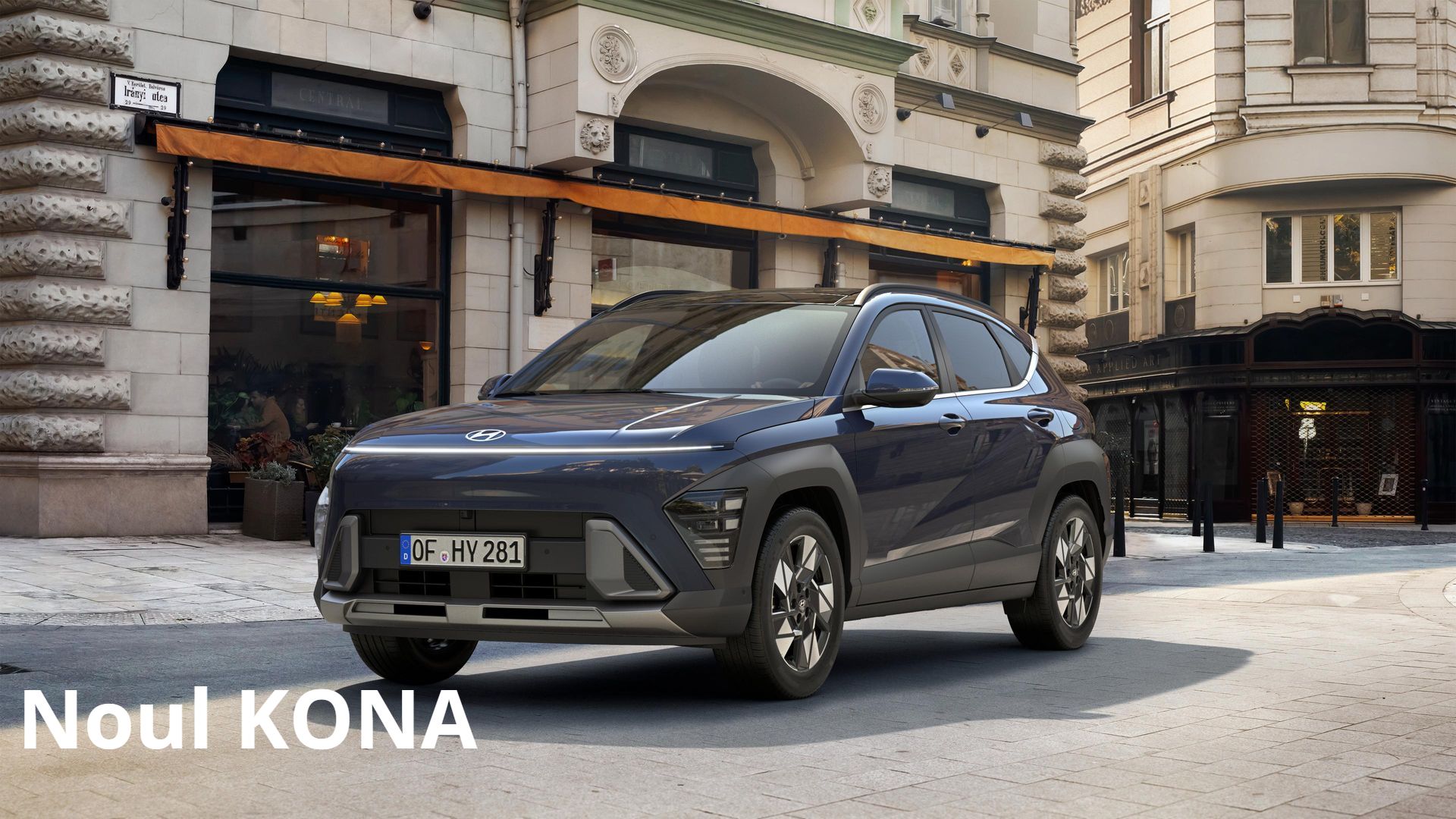 A blue hyundai kona is parked in front of a building on a city street. Kona
