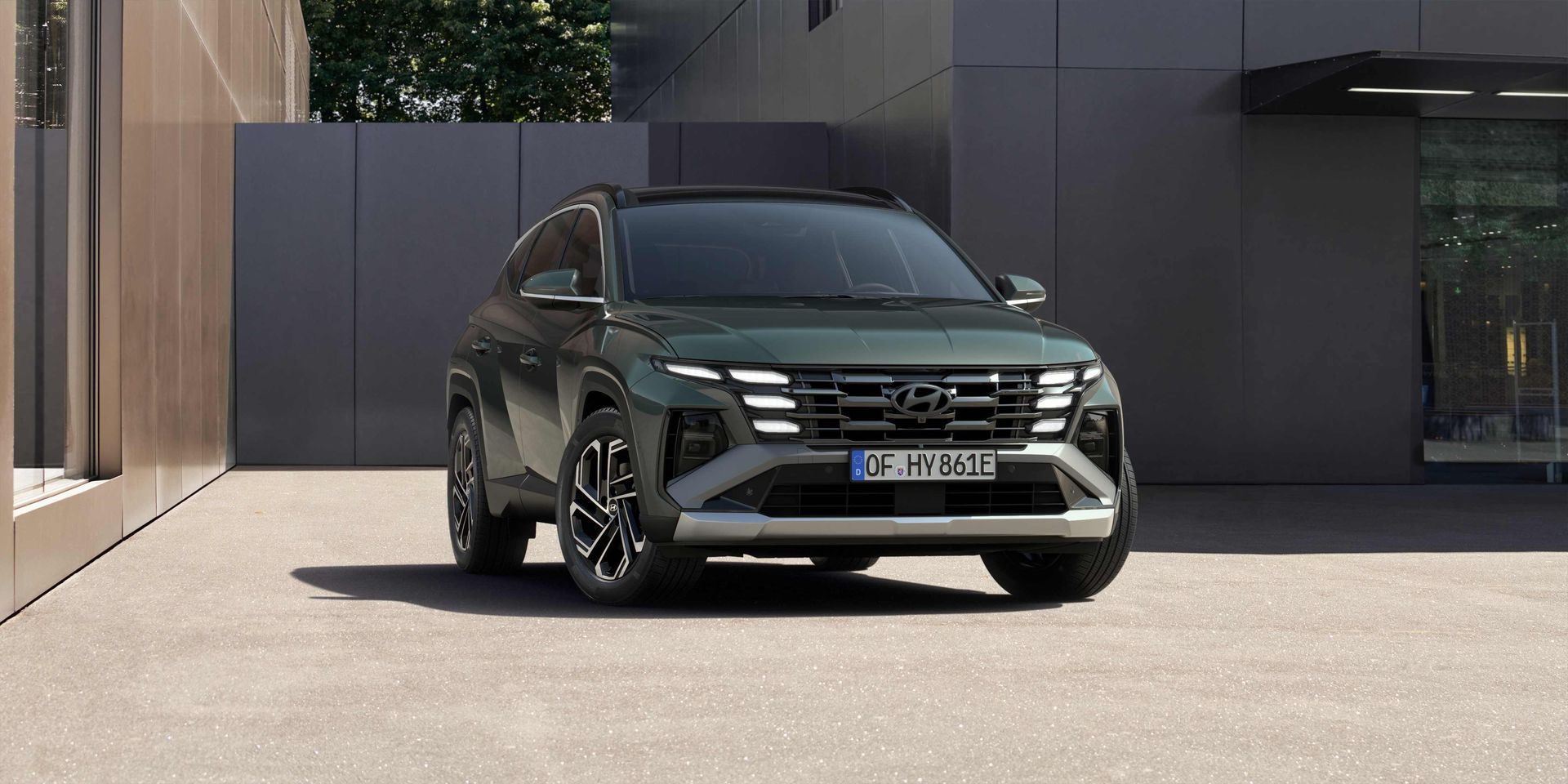 A green suv is parked in front of a building.
