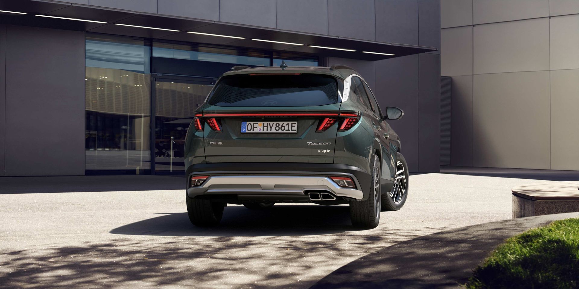 A green hyundai tucson is parked in front of a building.