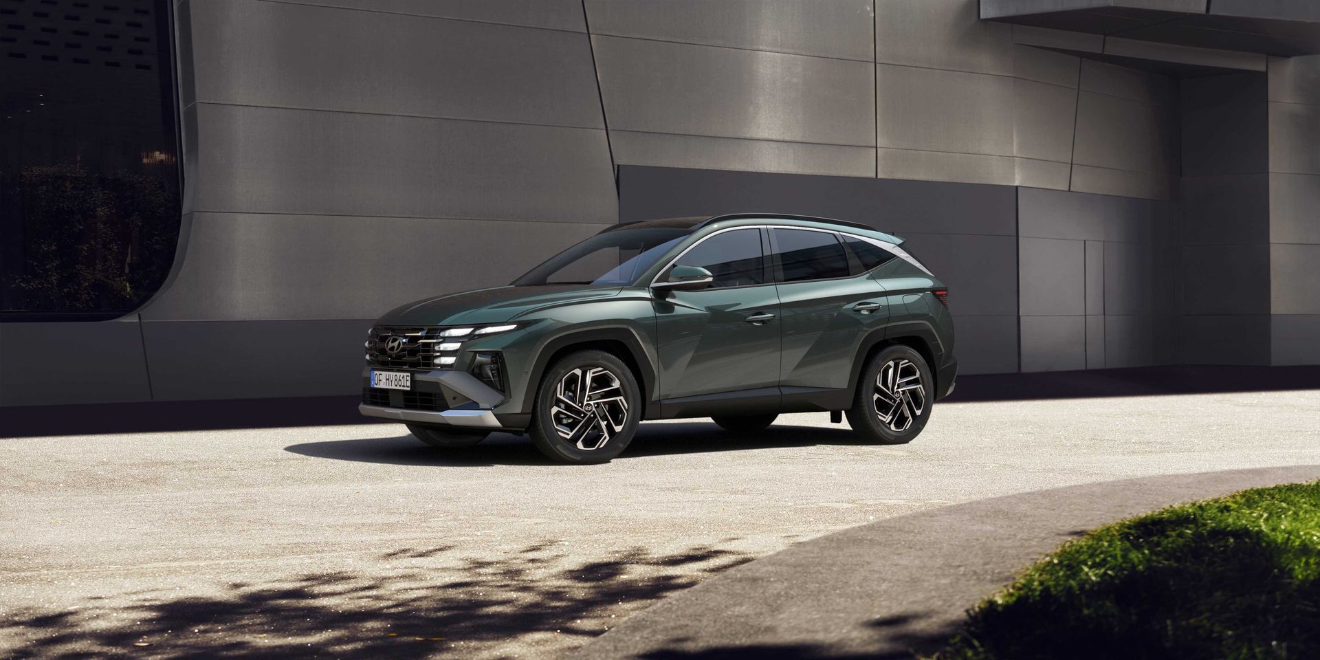 A green suv is parked on the side of the road in front of a building.