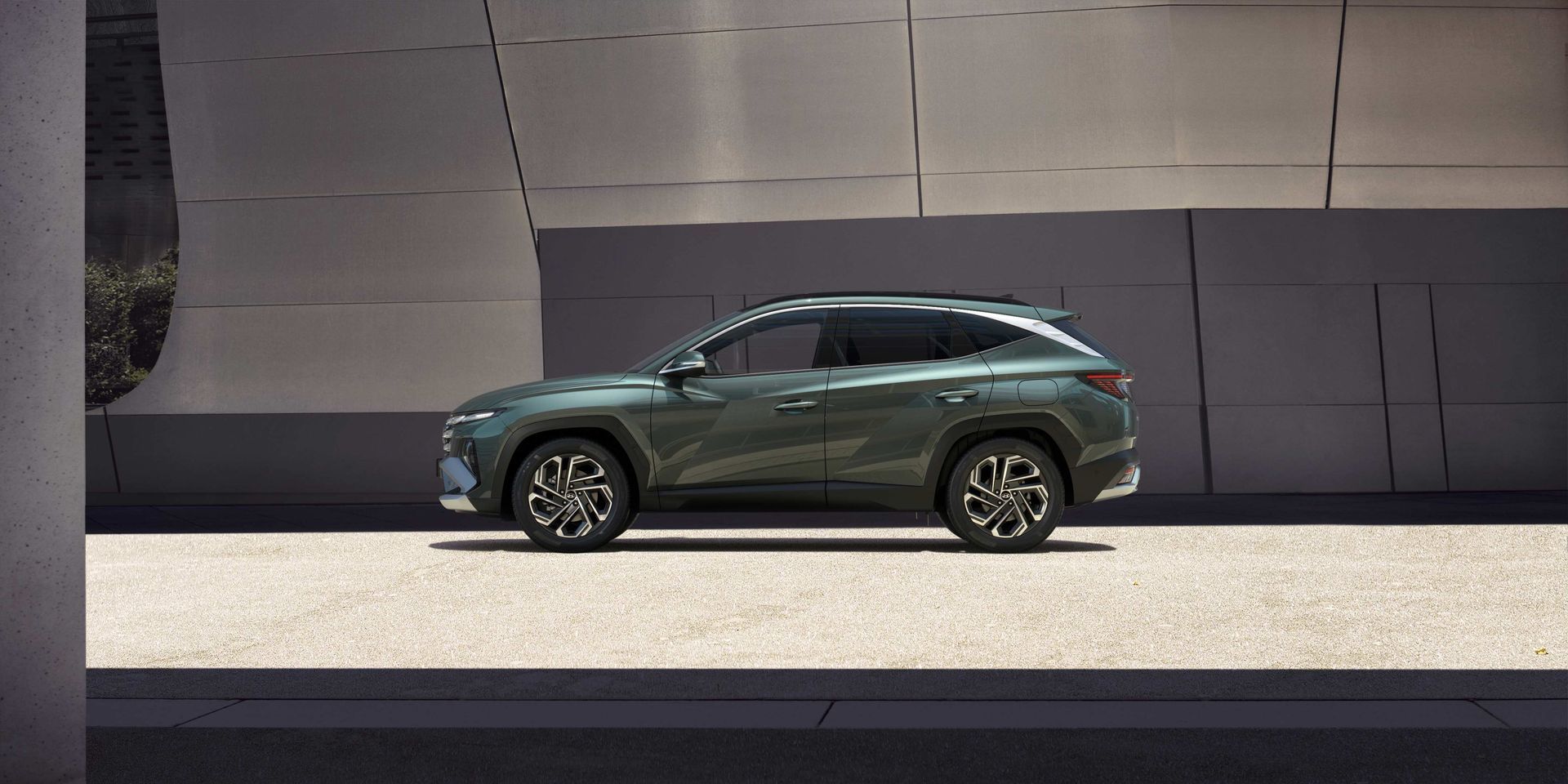 A green suv is parked on the side of the road in front of a building.