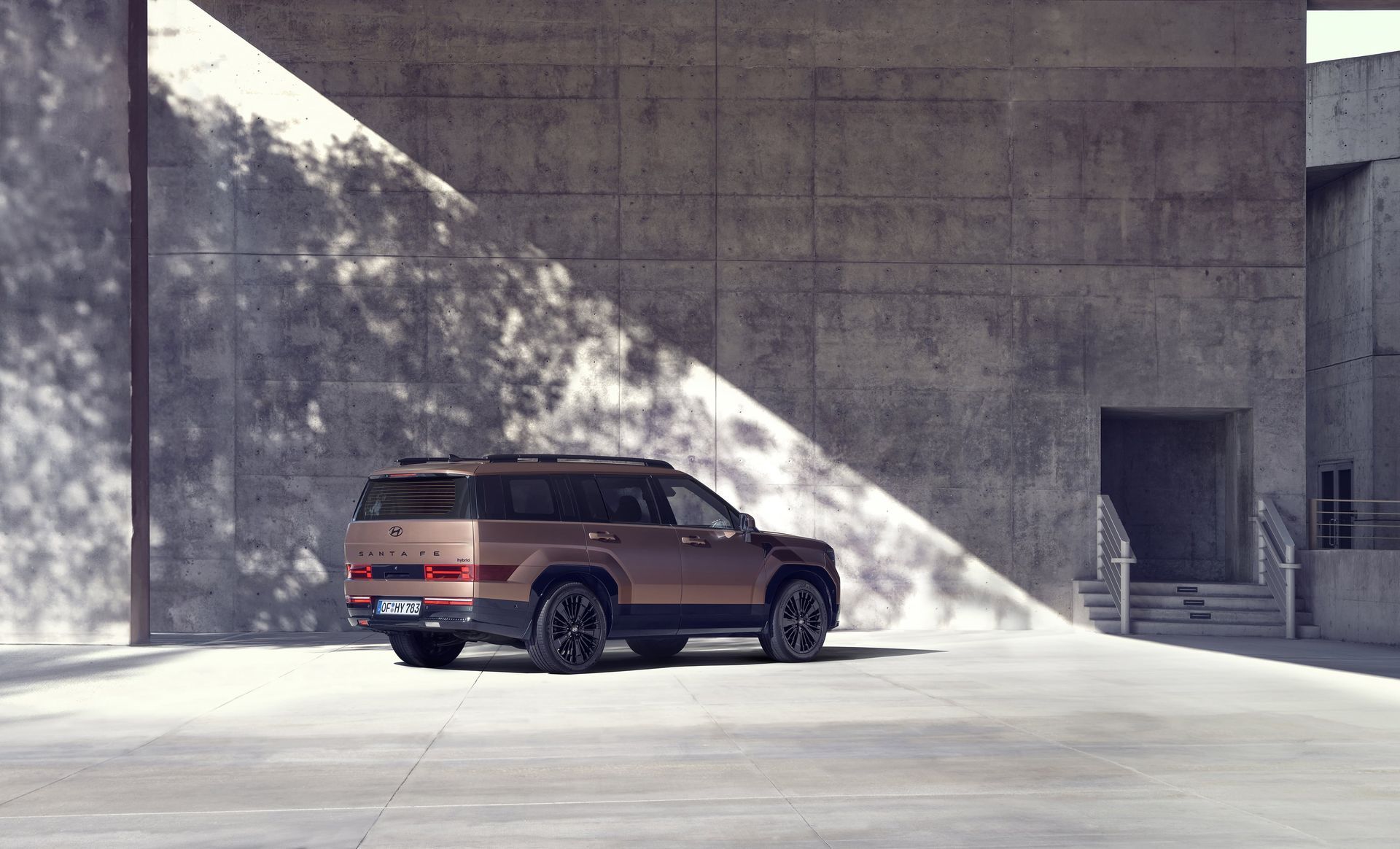 A brown suv is parked in front of a concrete wall.