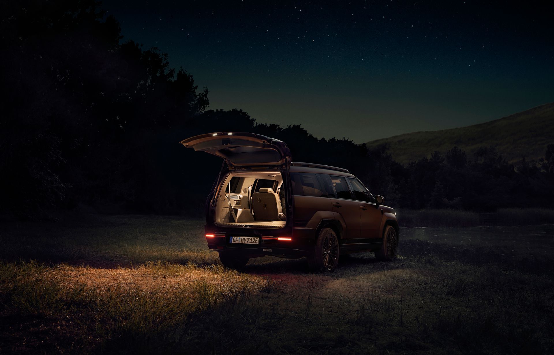 A car with its trunk open is parked in a field at night. Santa Fe