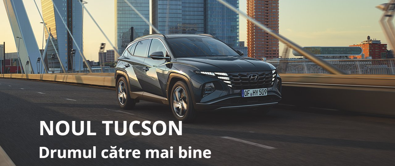 A black tucson is driving on a bridge in a city.