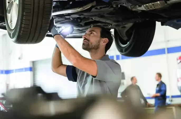 A man is working under a car in a garage.