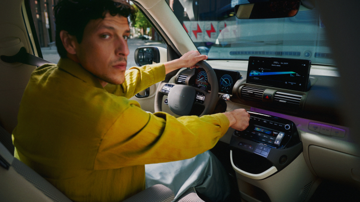 A man in a yellow shirt is driving a car. Inster