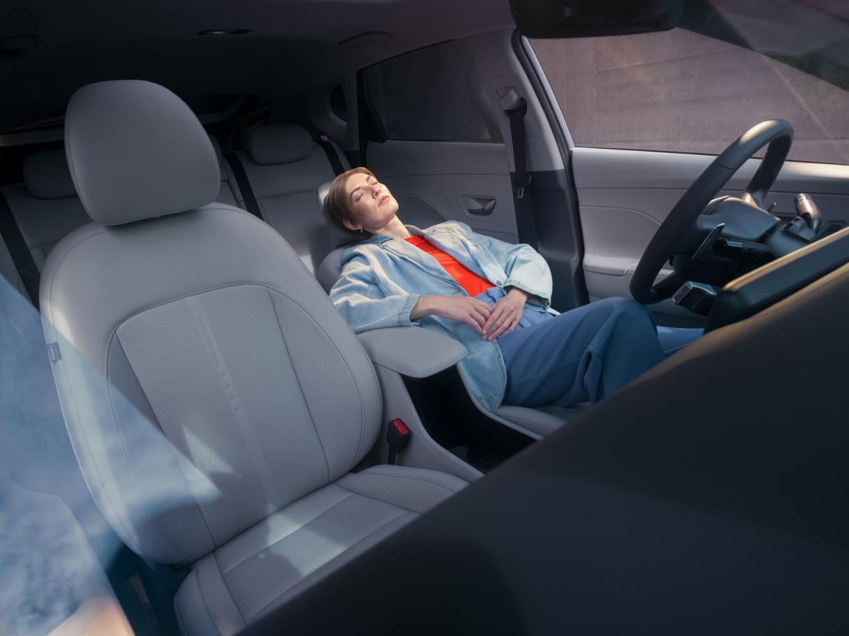 A man is sleeping in the back seat of a car. Kona Electric