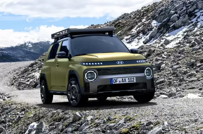 A yellow car with a roof rack is driving down a rocky road. Inster