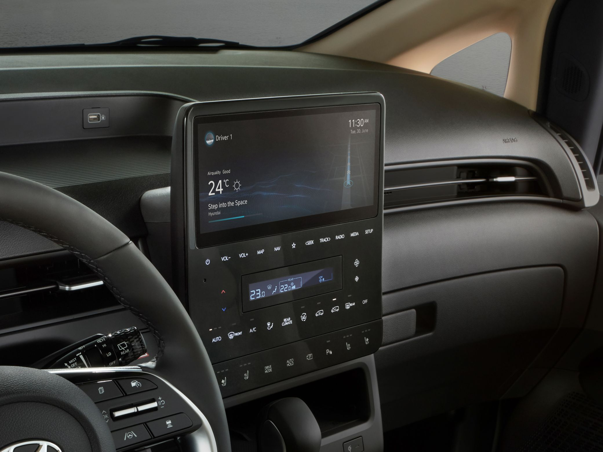 A car dashboard with a steering wheel and a radio. Staria