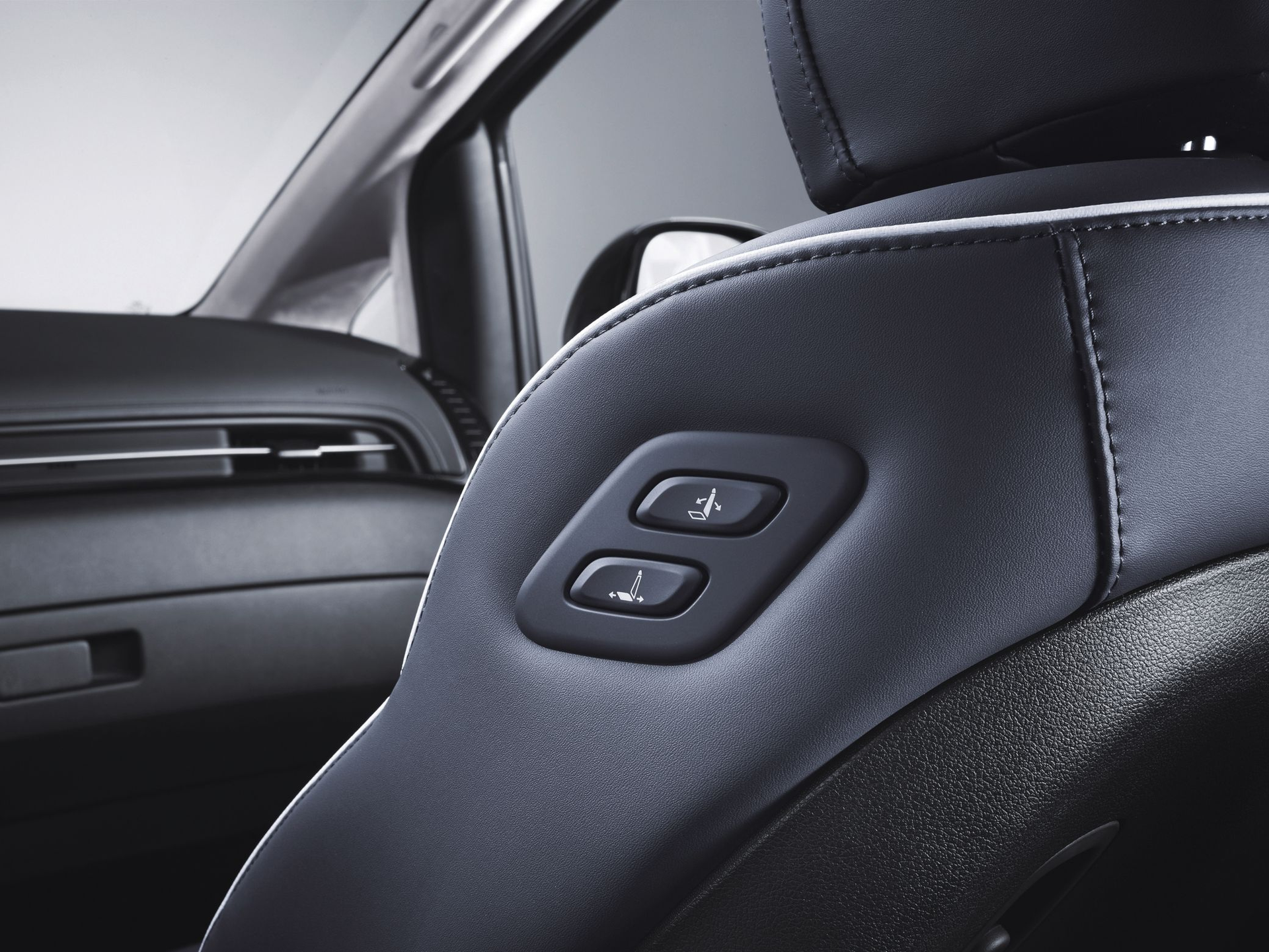 A close up of a car seat with two buttons on it Staria
