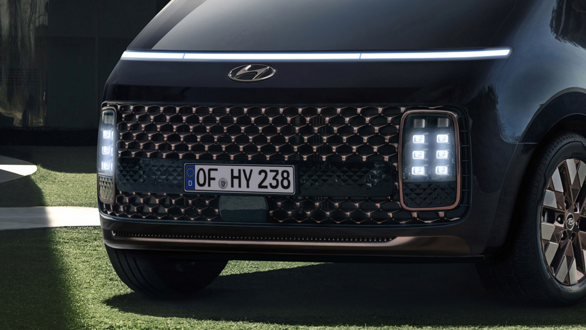 A black car with a license plate that says of hy 238 is parked on the grass. Staria