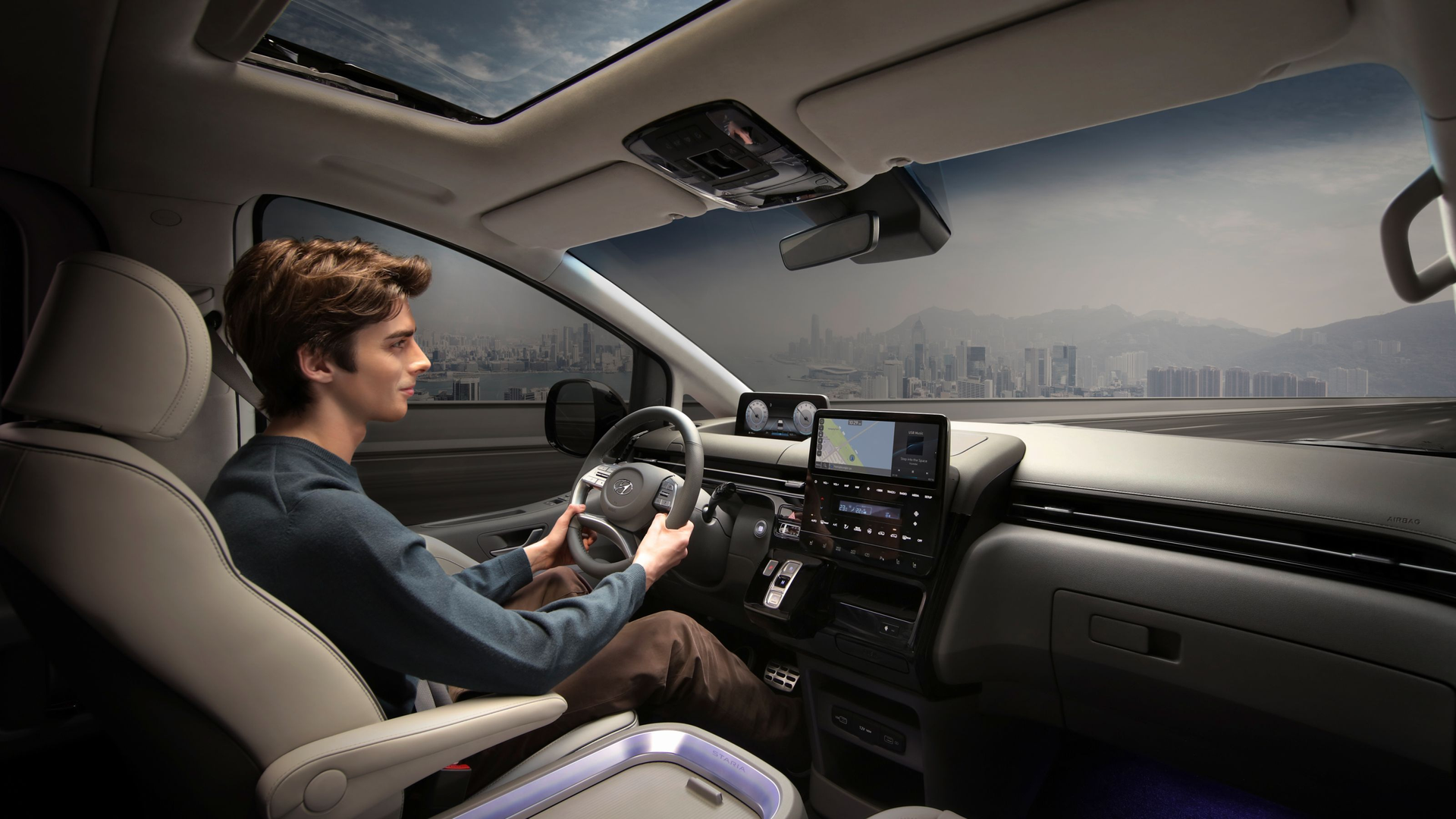 A man is sitting in the driver 's se at of a car.Staria