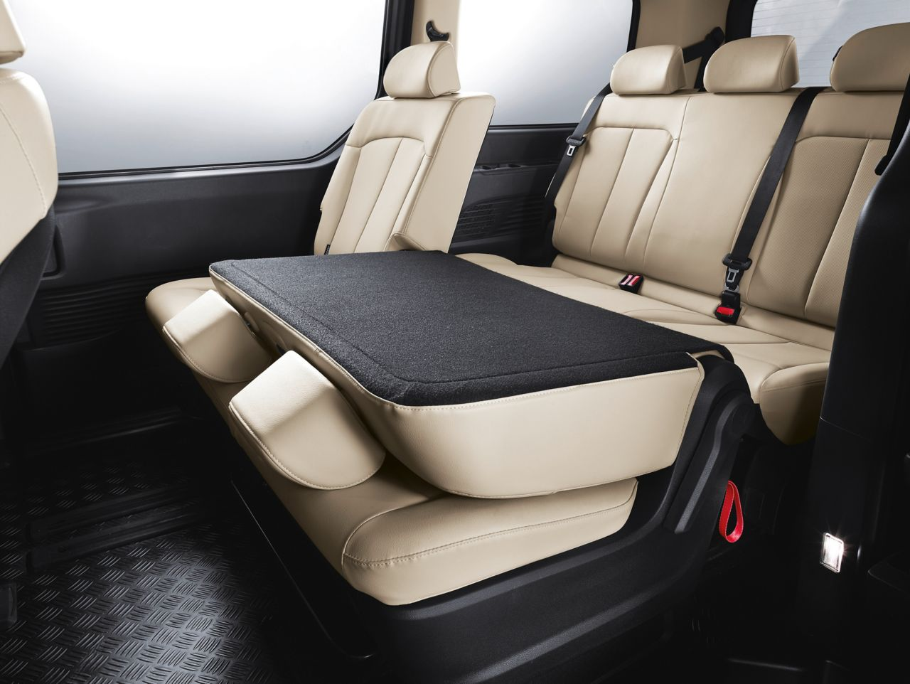 The back seat of a car has a black cushion on it Staria