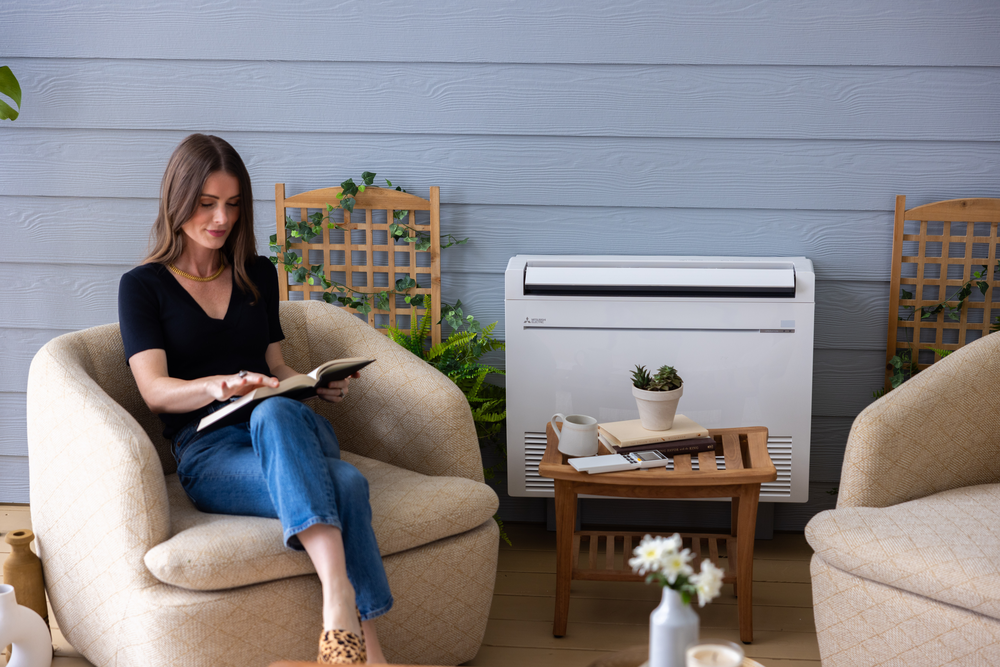 A woman is sitting in a chair reading a book in a living room.
