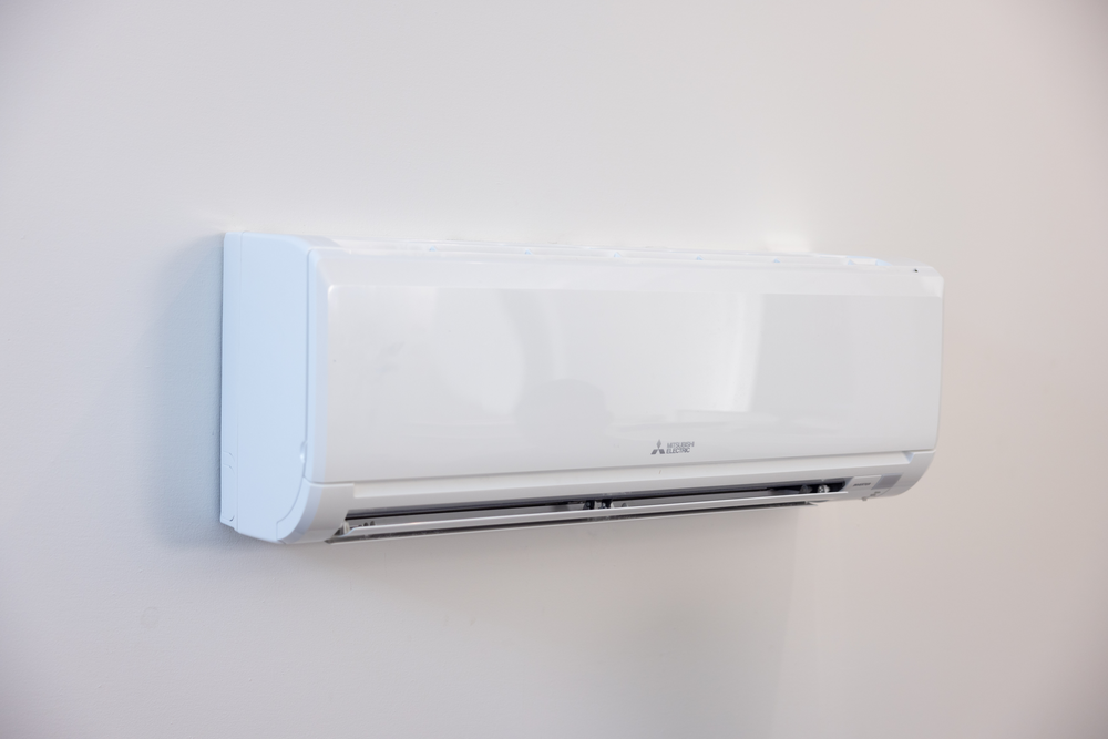 A white air conditioner is hanging on a white wall.