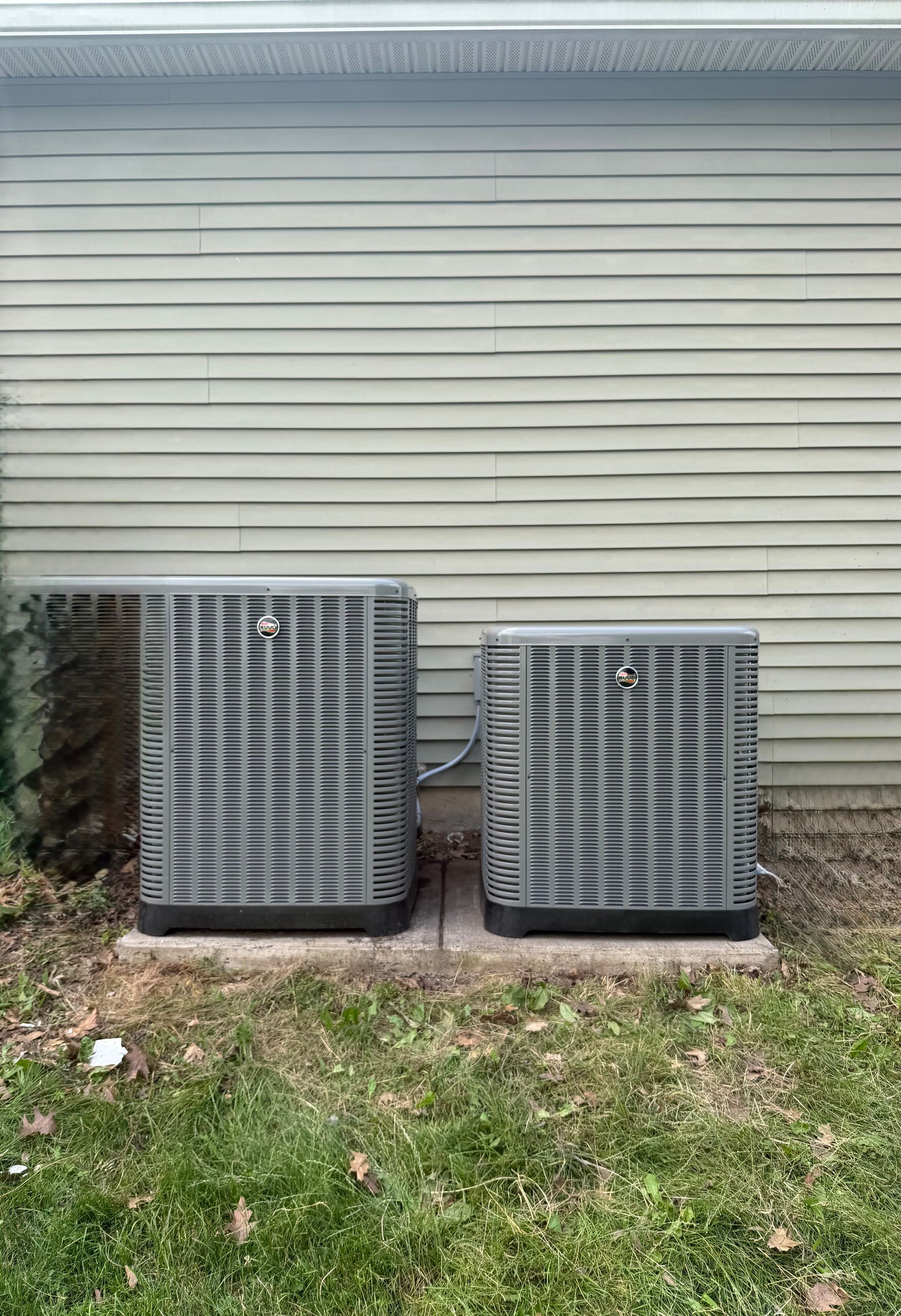 A large air conditioner is sitting in the grass next to a house.