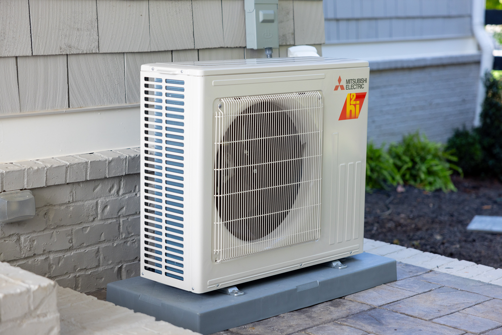 A mitsubishi air conditioner is sitting outside of a house.