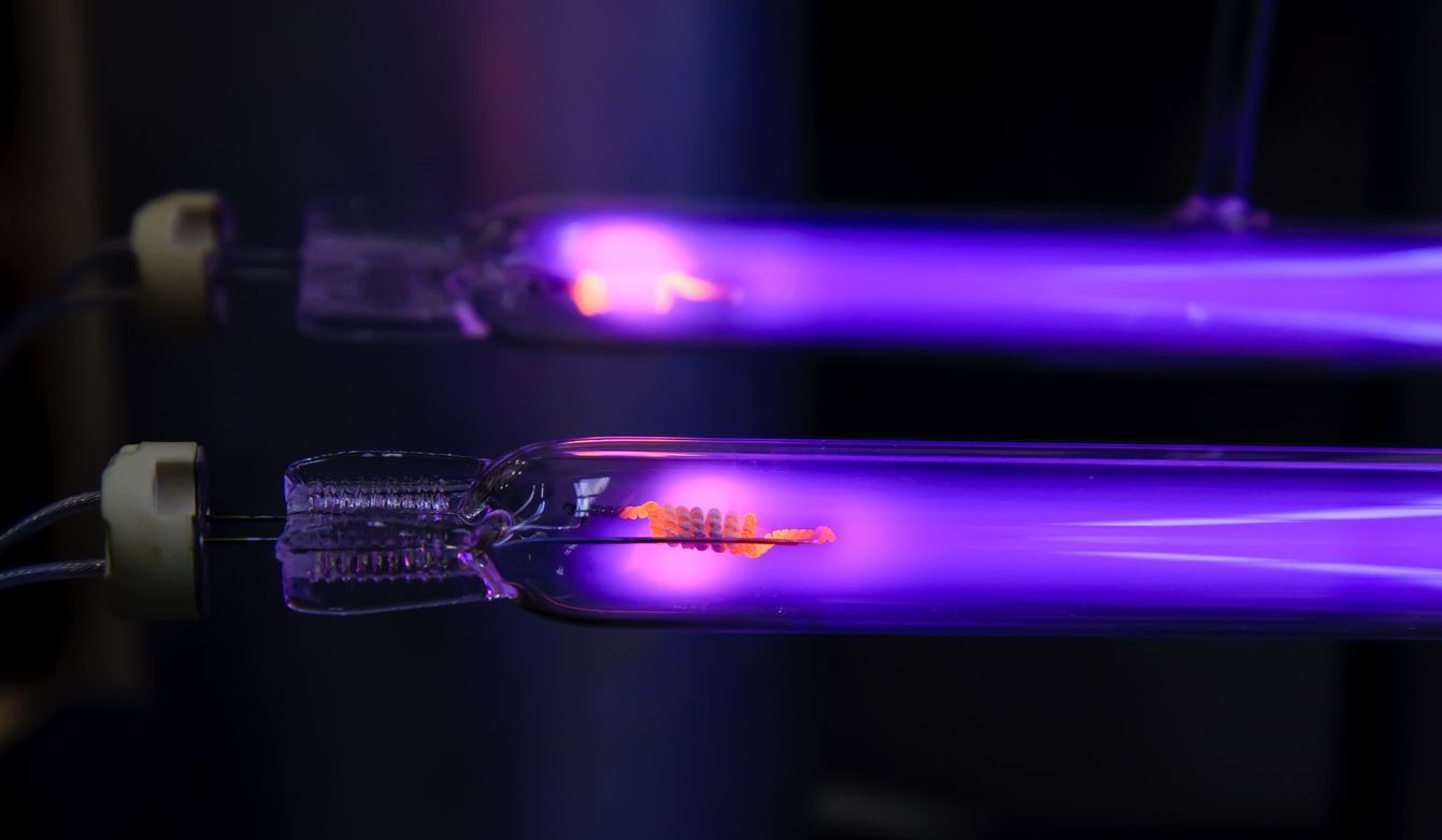 Two purple light bulbs are glowing in the dark.