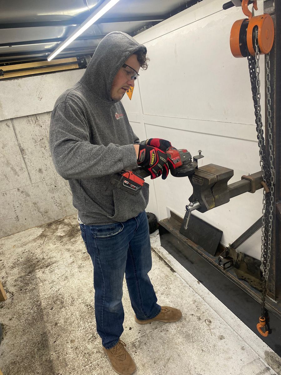 A man in a hoodie is using a drill in a room.