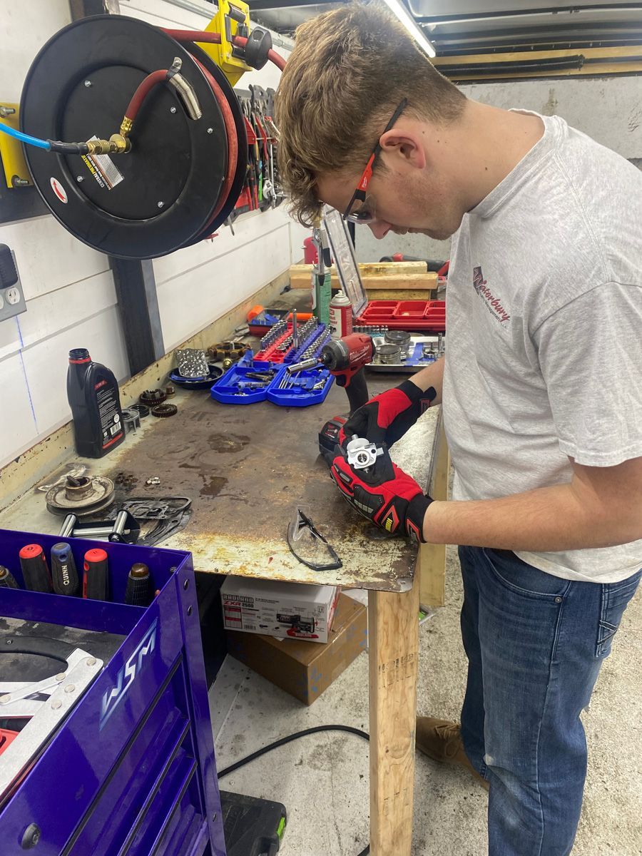 A man is working on a piece of equipment in a garage.