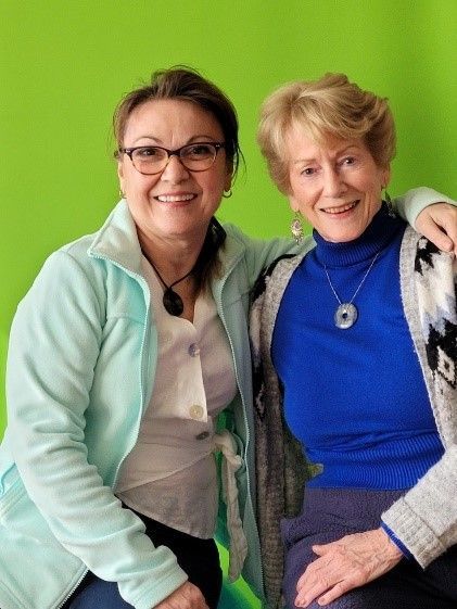 Two women are posing for a picture and one is wearing a blue sweater