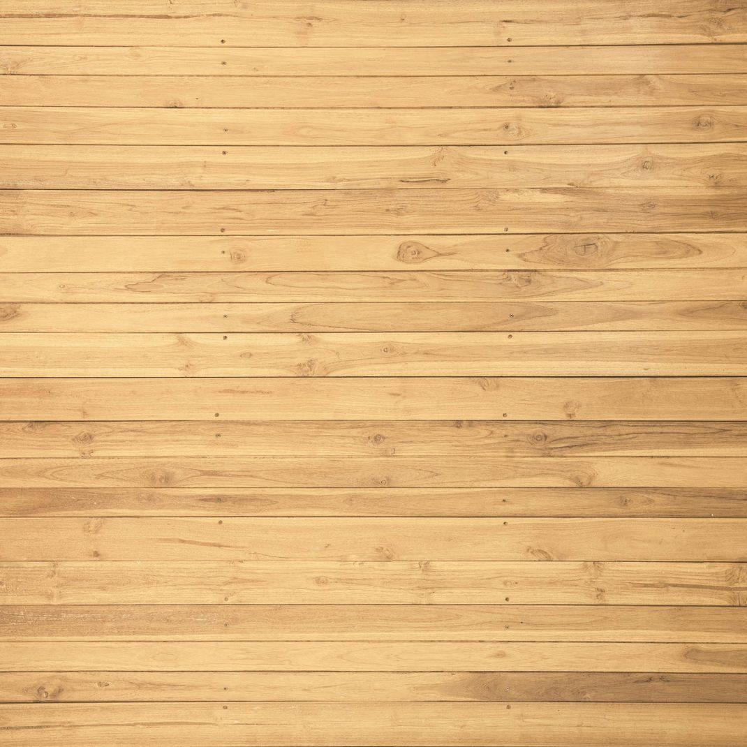 Wooden planks arranged horizontally, light brown color with visible wood grain and nail heads.