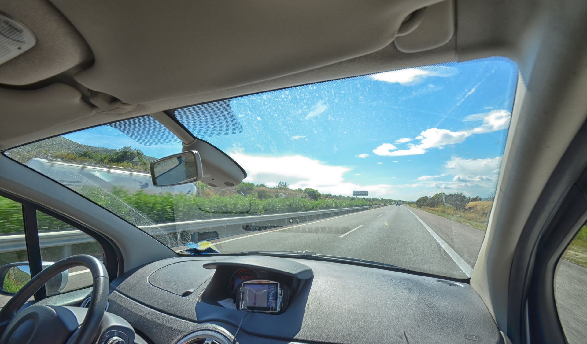A car is driving down a highway on a sunny day