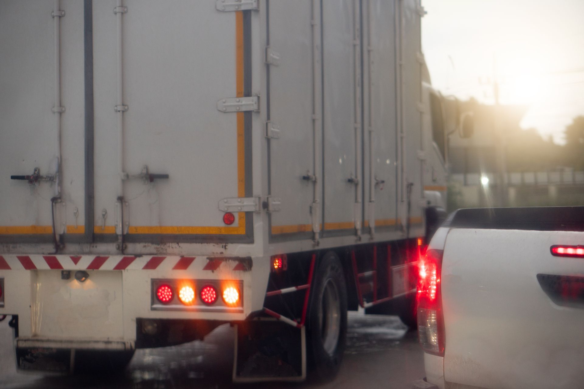 A white truck is driving next to a white truck on a city street.