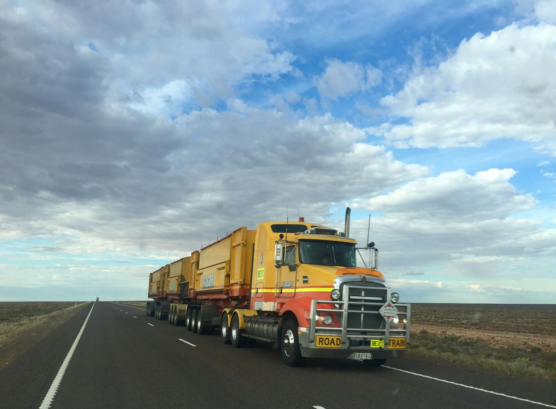 A yellow and red semi truck is driving down a highway