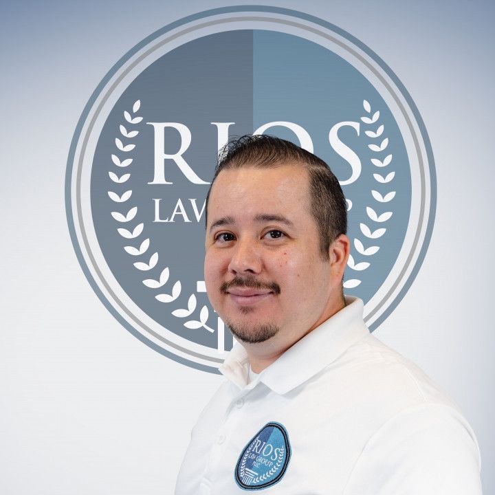 Man with a goatee and white polo shirt stands in front of Rios Law Group logo.