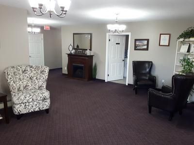 Empty hotel lobby with chairs, carpeted floor, fireplace, and wall lamps
