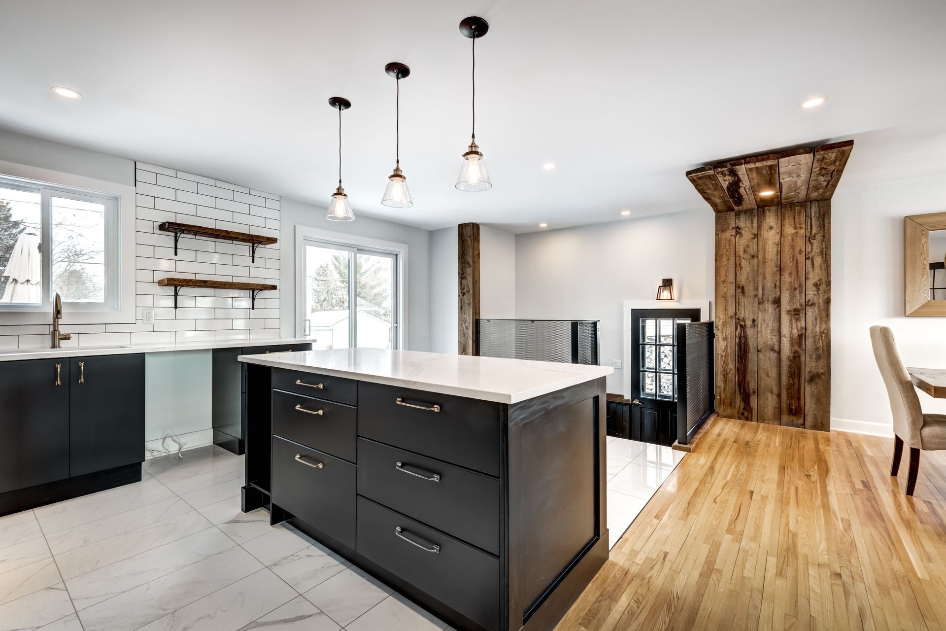 Modern kitchen with dark cabinetry, white countertops, island, and wood accents.