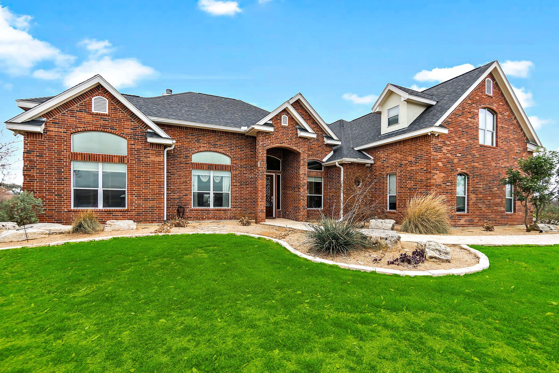 Brick house with a green lawn under a blue sky. Brick house with a green lawn under a blue sky.