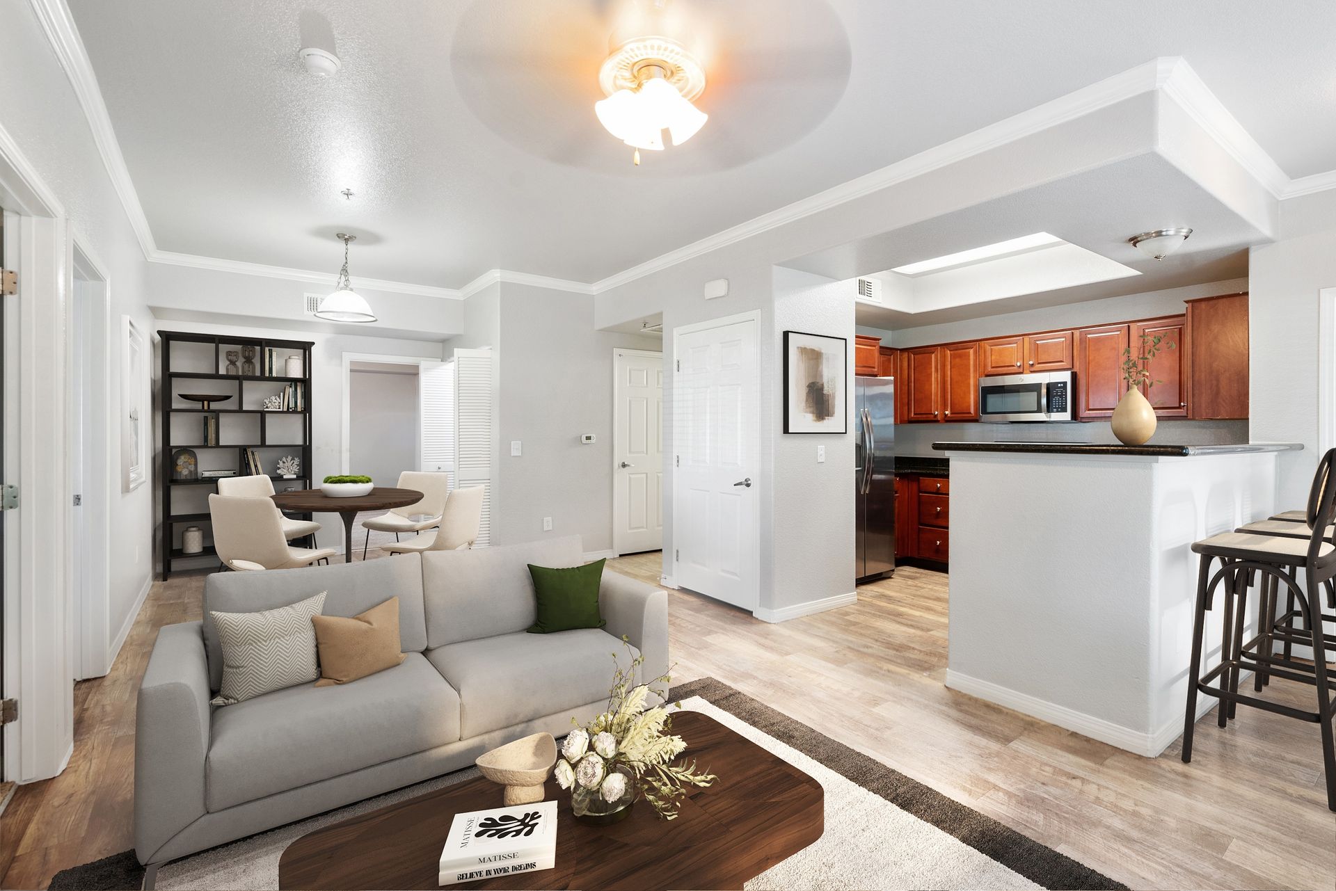 Open-concept living area with a light gray sofa, dining table, and a kitchen with a bar counter at Wolf Ranch Apartments.