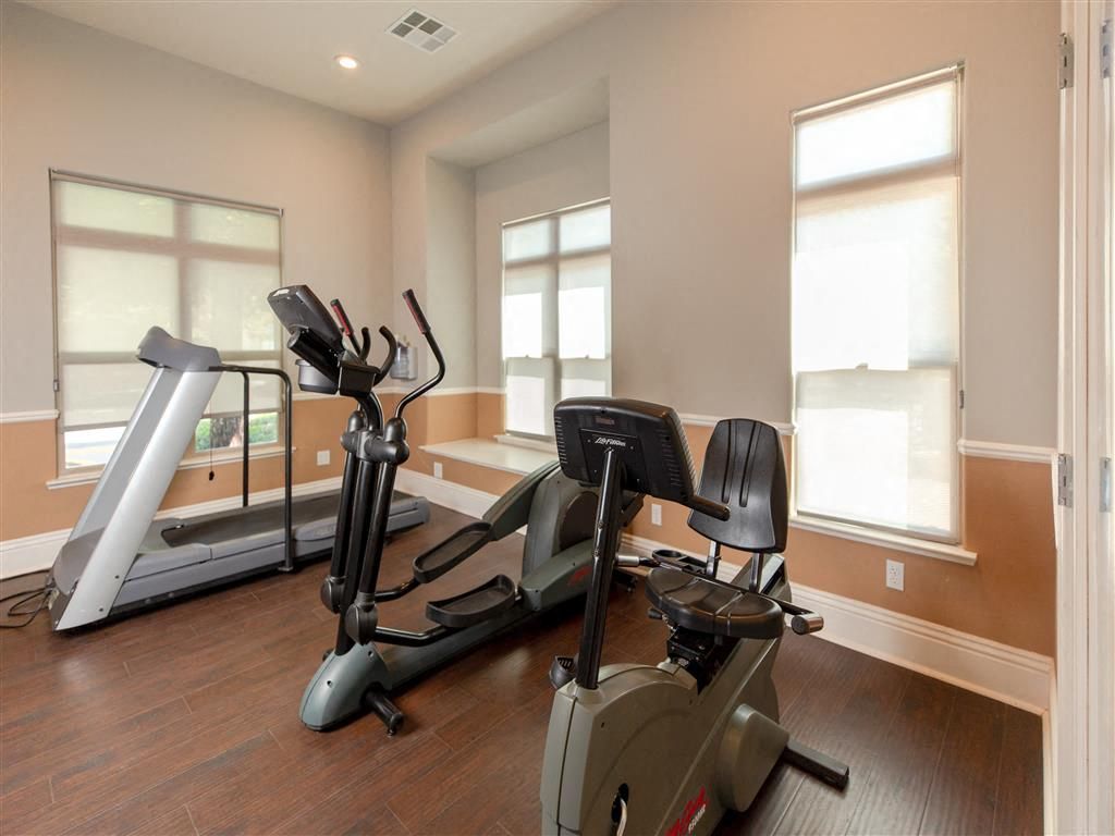 Interior of a communal fitness center with treadmill, elliptical, and stationary bike at Wolf Ranch Apartments.
