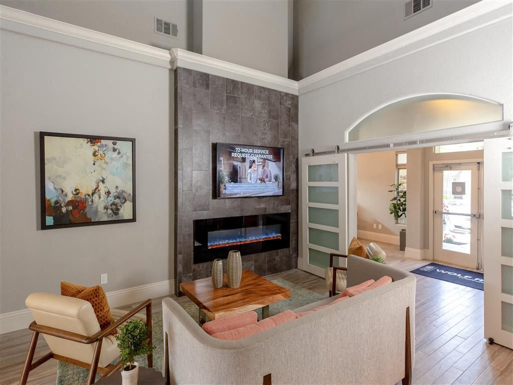Indoor apartment lobby with seating area, fireplace, and glass entry doors at Wolf Ranch Apartments.