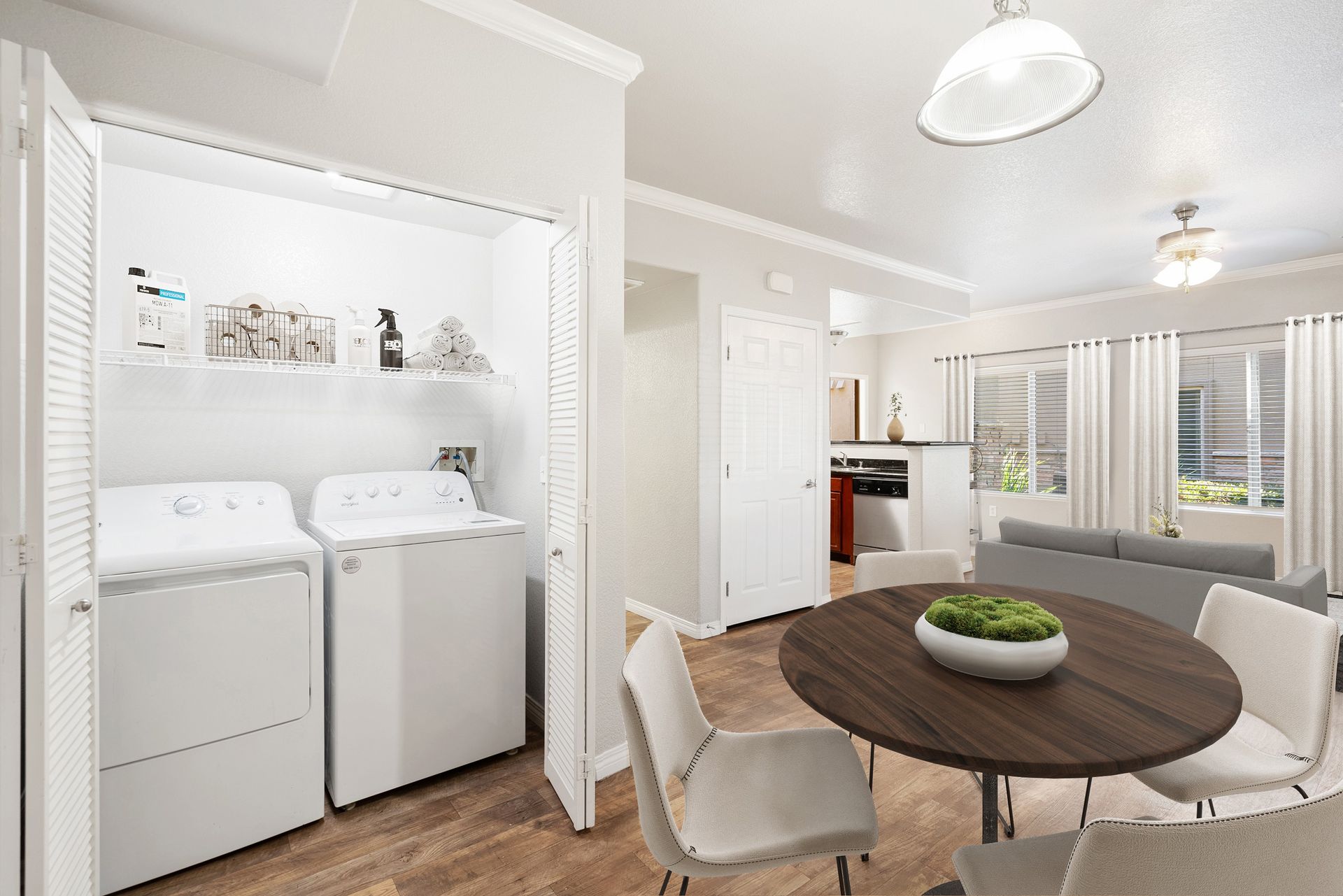 Laundry closet with a washer and dryer, shelves with towels, near a round dining table at Wolf Ranch Apartments.