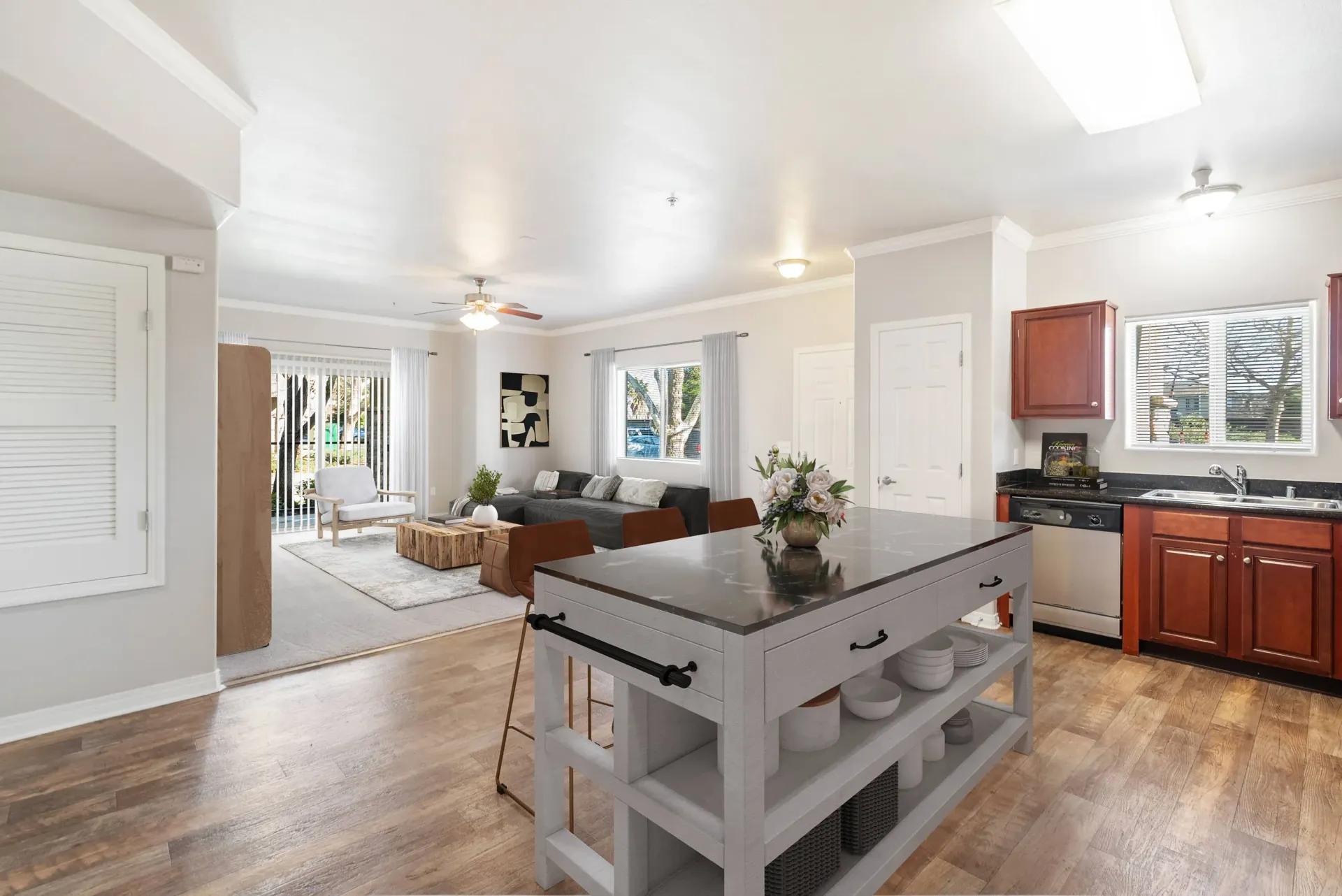 Open-concept living area with a kitchen island, seating, and a sliding glass door to the outdoors at Wolf Ranch Apartments.