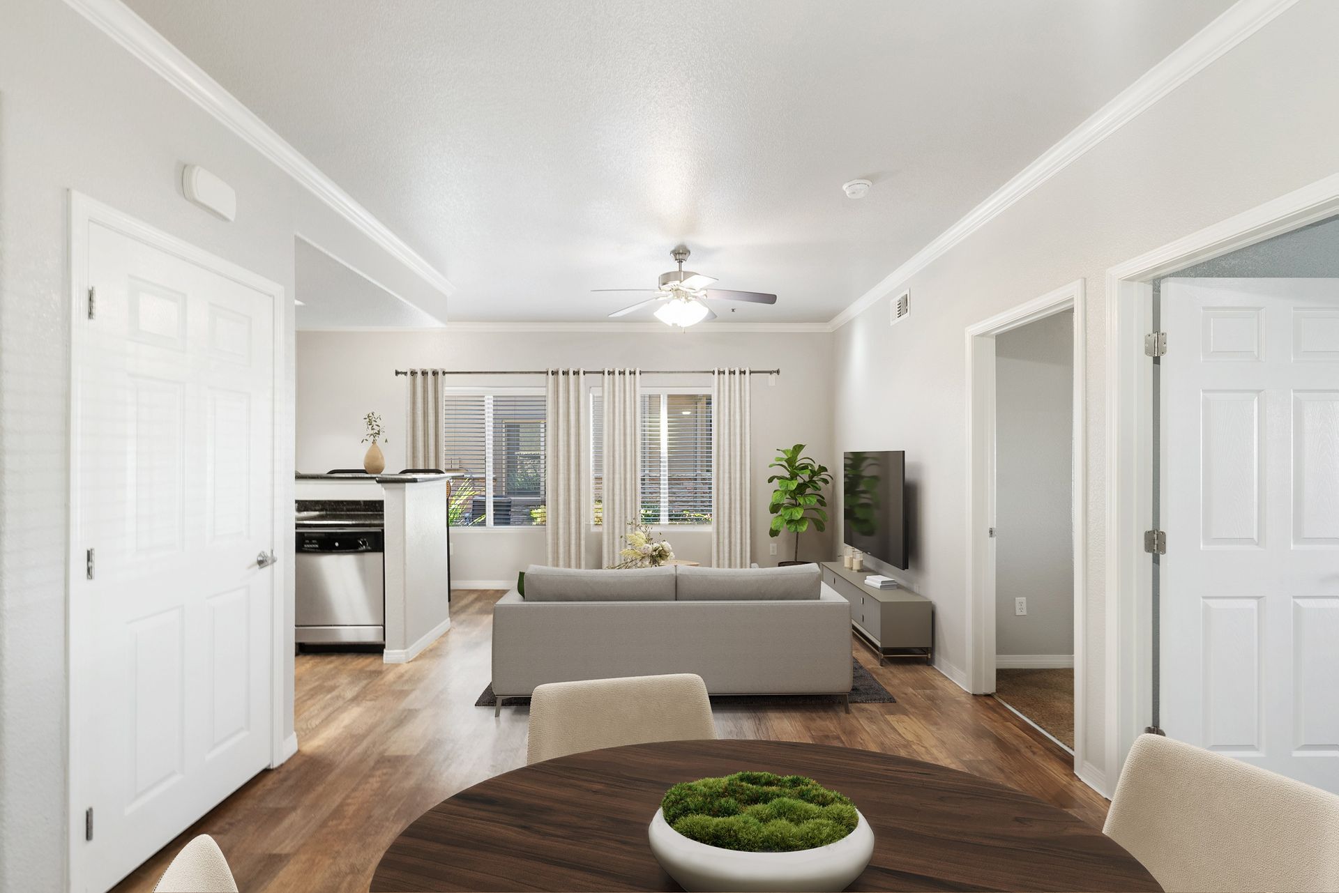 Open-concept living room with gray sofa, TV, dining table, and kitchen area at Wolf Ranch Apartments.