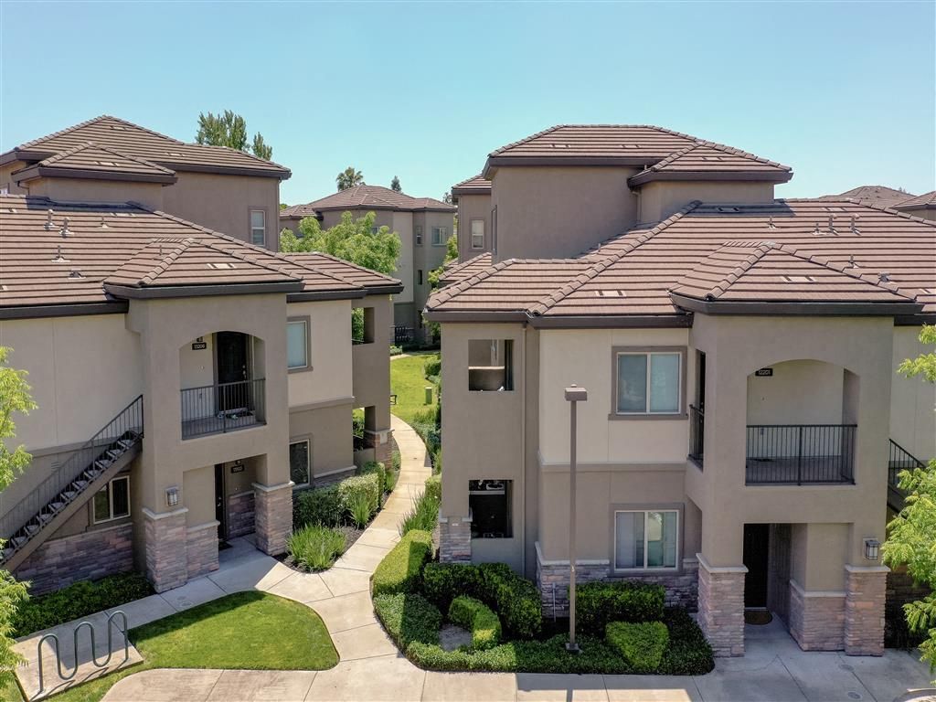 Aerial view of beige apartment buildings with tiled roofs, walkways, and landscaped courtyards at Wolf Ranch Apartments.