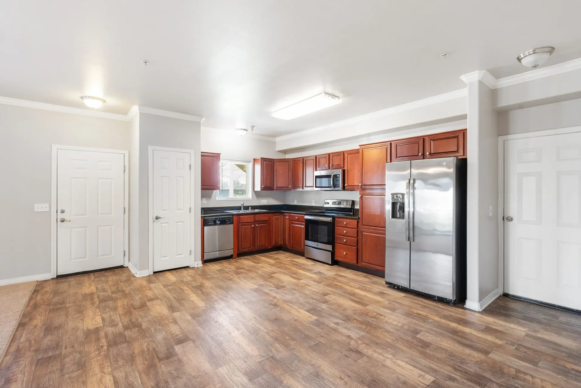 Open kitchen in apartment with stainless steel fridge, dishwasher, microwave, and wood cabinets at Wolf Ranch Apartments.