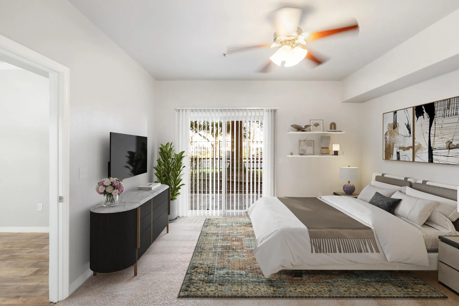 Bedroom in a modern apartment with a bed, dresser, wall TV, and sliding glass door to a patio at Wolf Ranch Apartments.